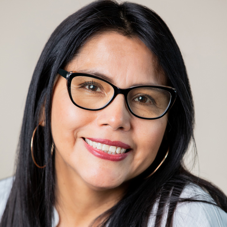 a woman wearing glasses and smiling at the camera